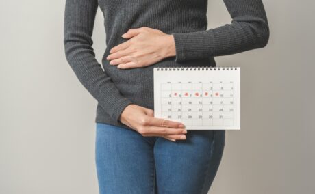 femeie care are un calendar în mână și își ține mâna la burtă