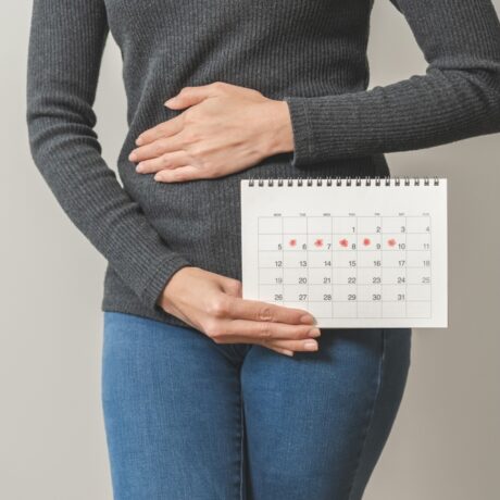 femeie care are un calendar în mână și își ține mâna la burtă