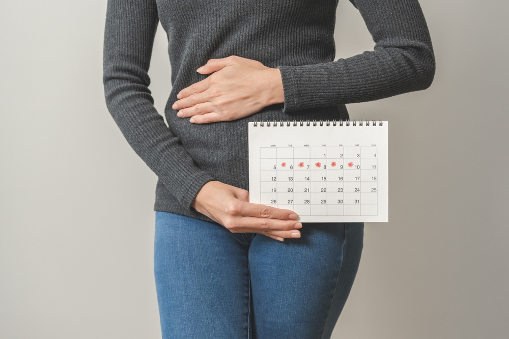 femeie care are un calendar în mână și își ține mâna la burtă