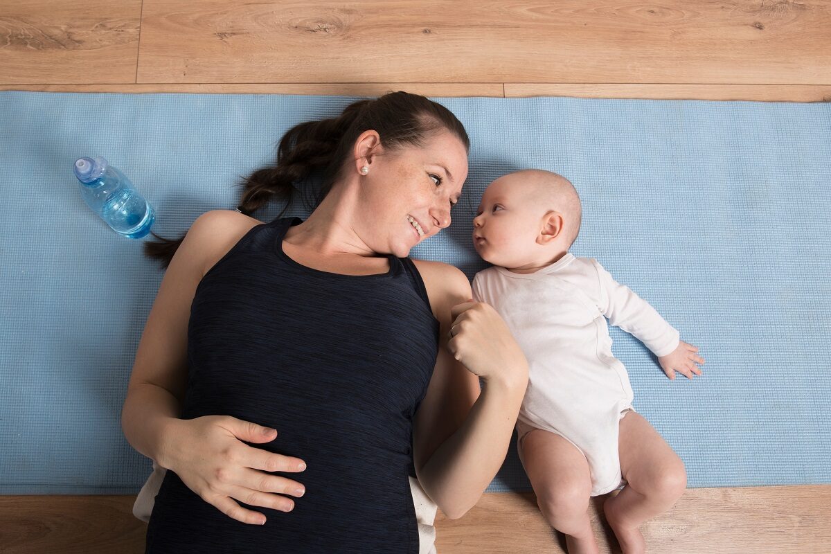 Mama și bebelușul stau întinși pe podea