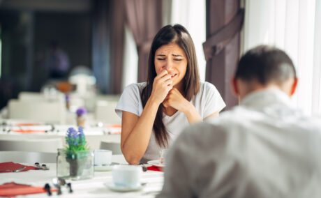 Femeie care plânge în fața unui bărbat care se află la restaurant