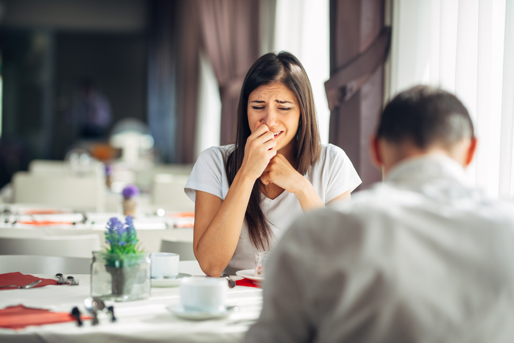 Femeie care plânge în fața unui bărbat care se află la restaurant