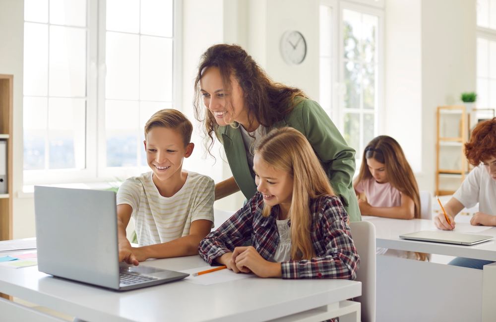 Profesoară care explică elevilor la computer