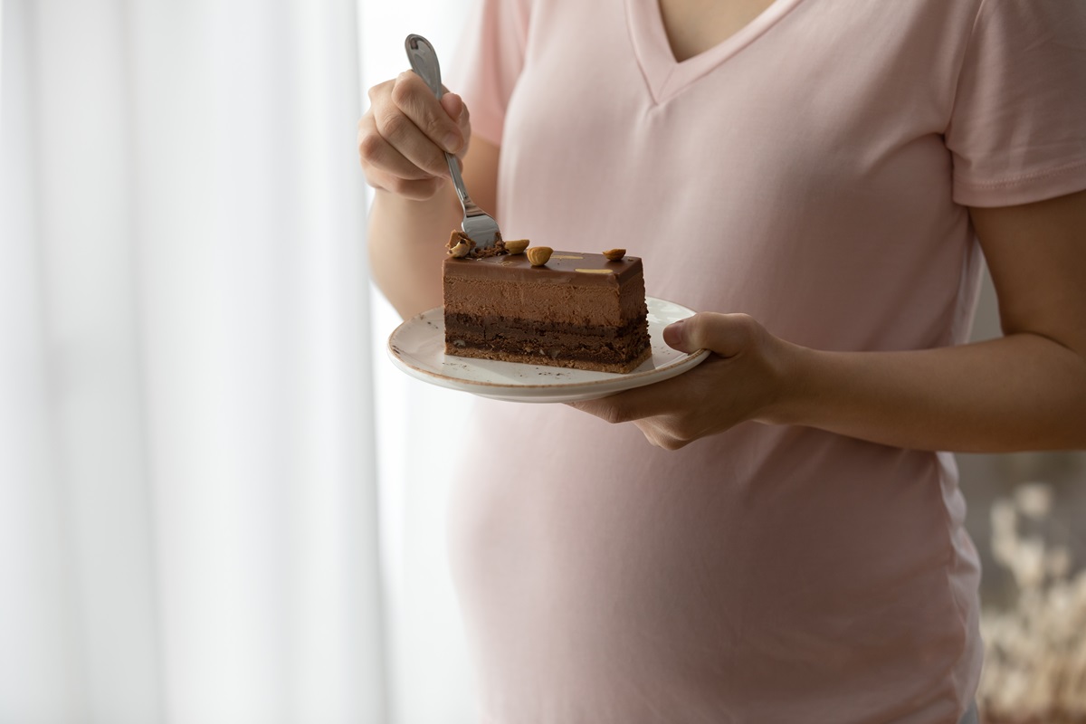 O mămică care mănâncă o felie de tort cu ciocolată