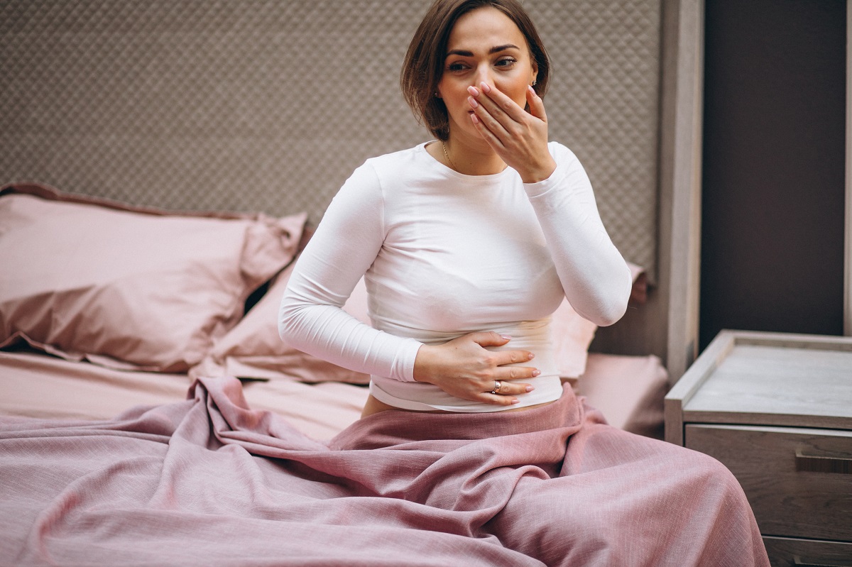 Gravidă stă pe marginea patului și are grețuri matinale