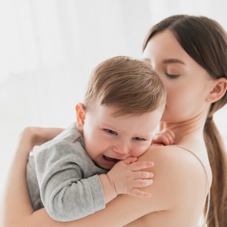 Mama ține în brațe bebelușul care plânge