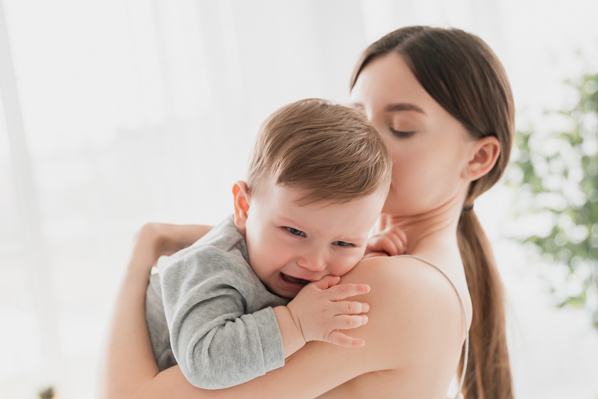 Mama ține în brațe bebelușul care plânge