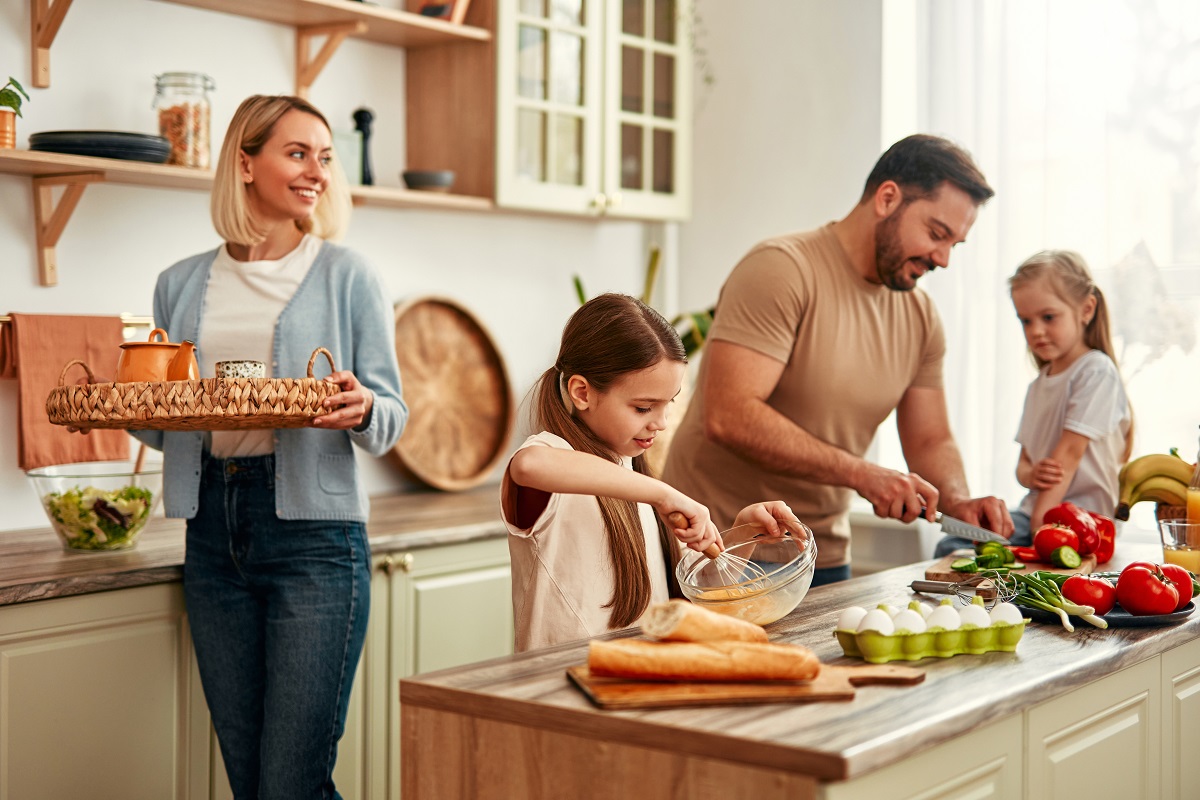 Mama, tata și cei doi copii sunt în bucătărie și pregătesc masa