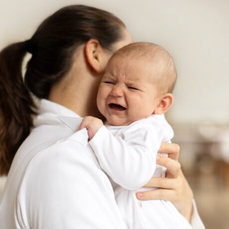 Mama ține bebelușul care plânge în brațe