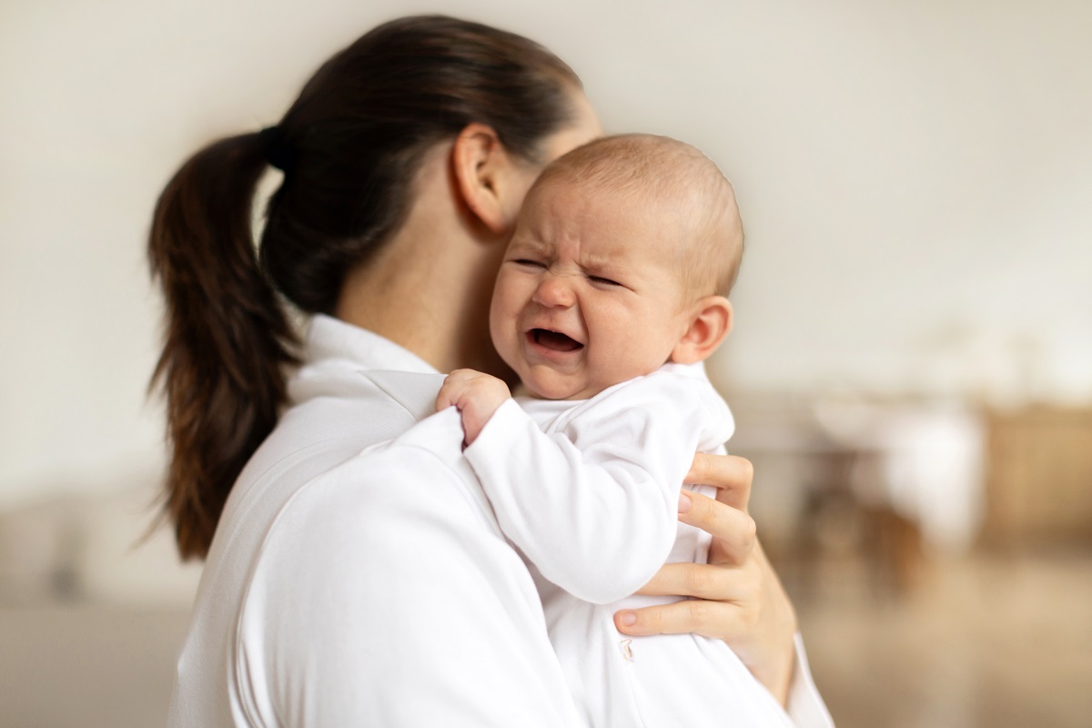 Mama ține bebelușul care plânge în brațe