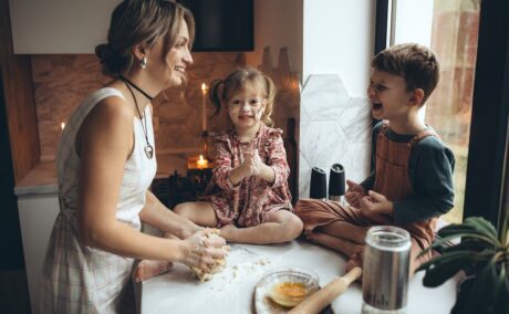 Mama și cei doi copii sunt la bucătărie și prepară un aluat pentru fursecuri