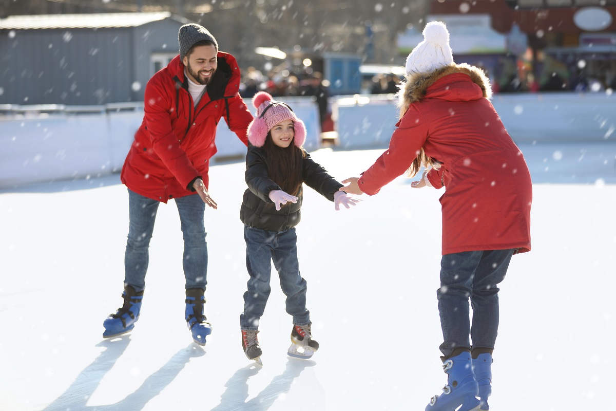 Mama, tata și fetița se distrează la patinoar