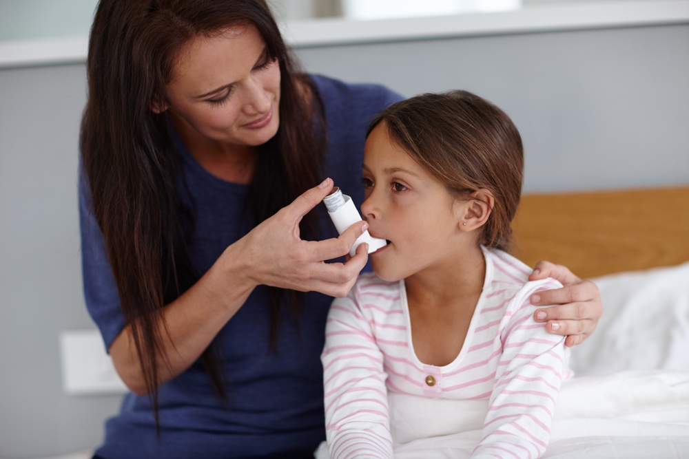 O mama care îi dă fetiței cu inhalator