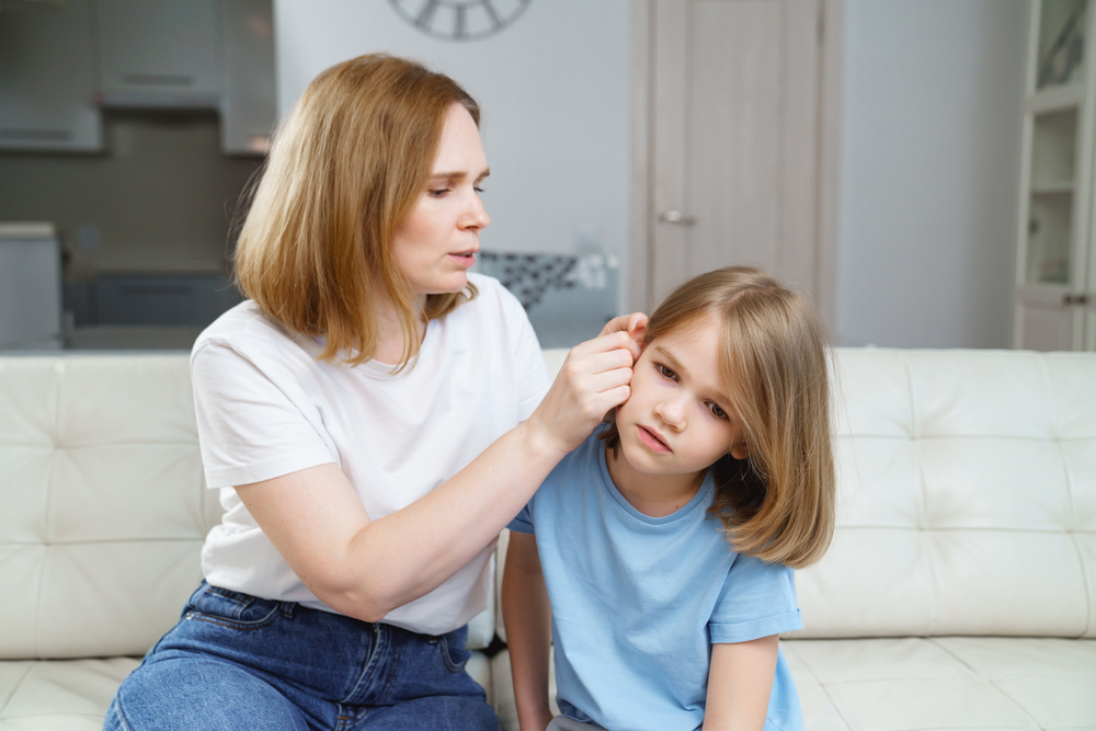 O mamă care verifică urechea fiicei sale