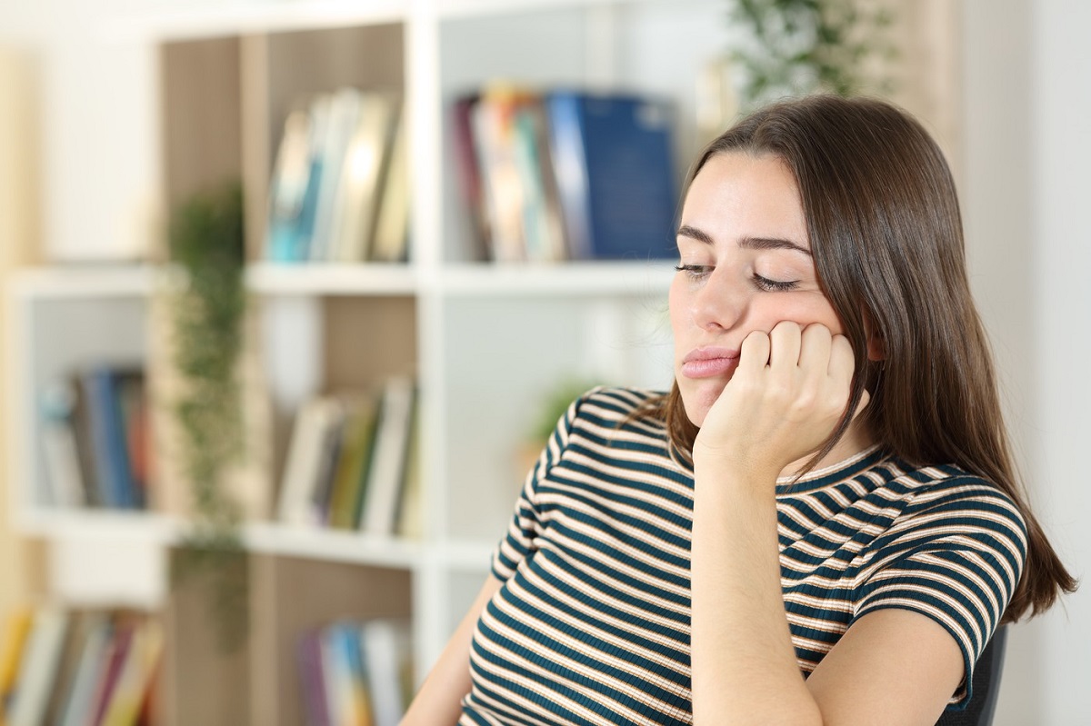 Adolescentă stă plictisită cu capul în palme