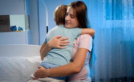 Mama își îmbrățișează copilul care refuză să doarmă singur