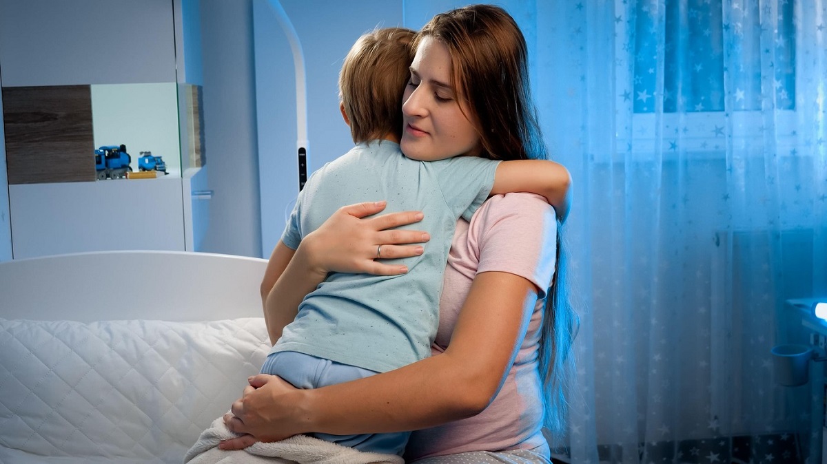 Mama își îmbrățișează copilul care refuză să doarmă singur