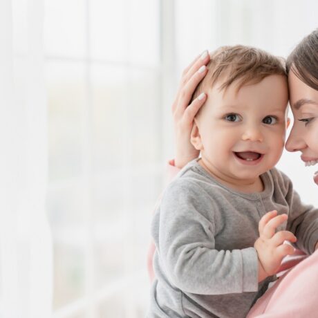 Mama își ține copilul în brațe fericită