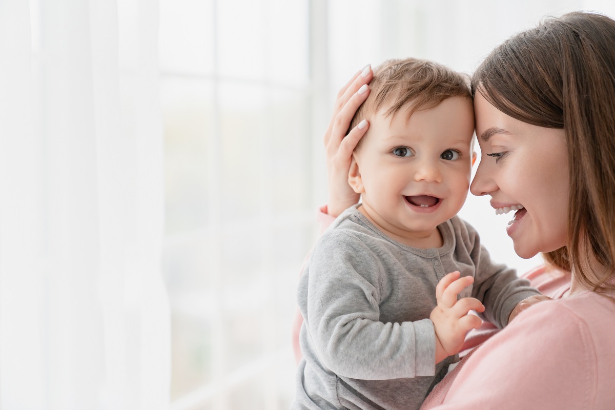 Mama își ține copilul în brațe fericită