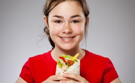 Fetiță ține în mână un wrap cu legume