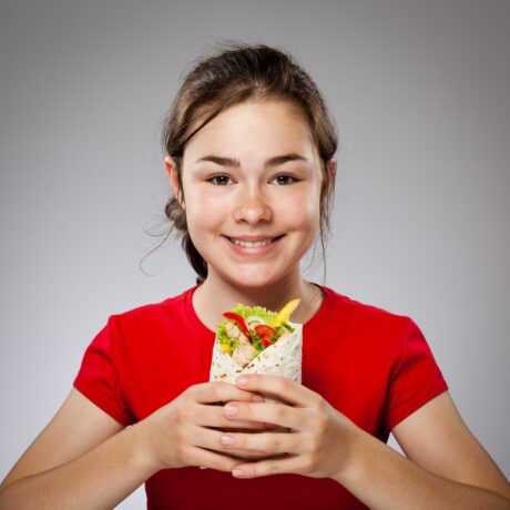 Fetiță ține în mână un wrap cu legume