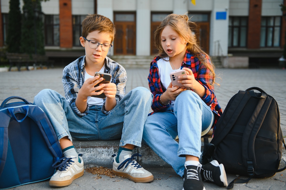 Doi copii care stau pe telefoane și privesc reclamele sugerate de aplicații