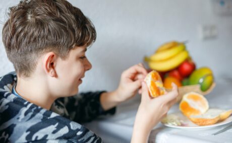 Băiat își desface o portocală