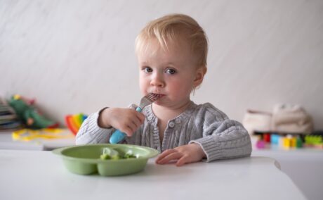 Copil mănâncă la masă cu furculița