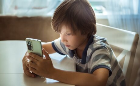 Băiat stă și se uită pe telefon