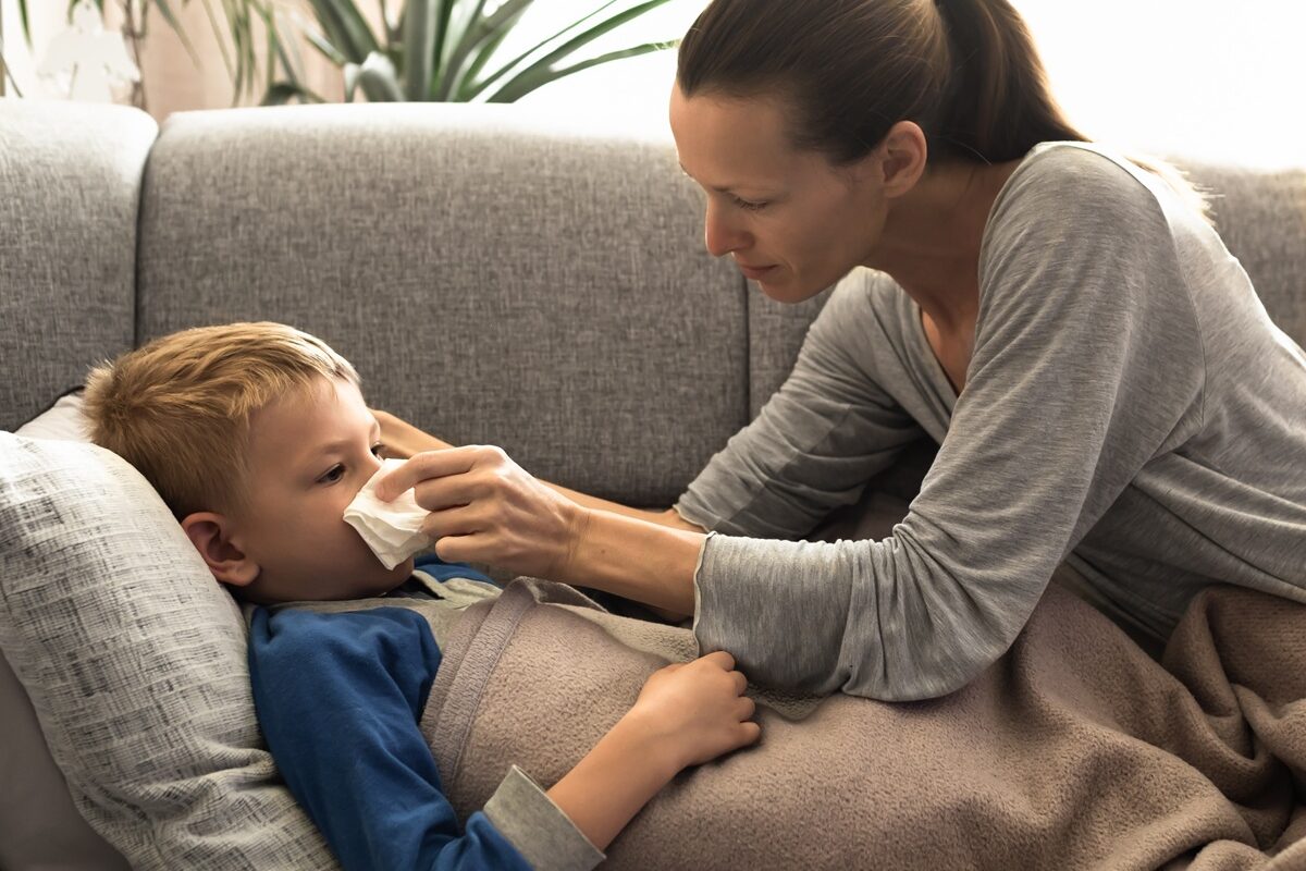 Mama îngrijește copilul răcit care stă în pat