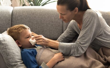 Mama îngrijește copilul răcit care stă în pat