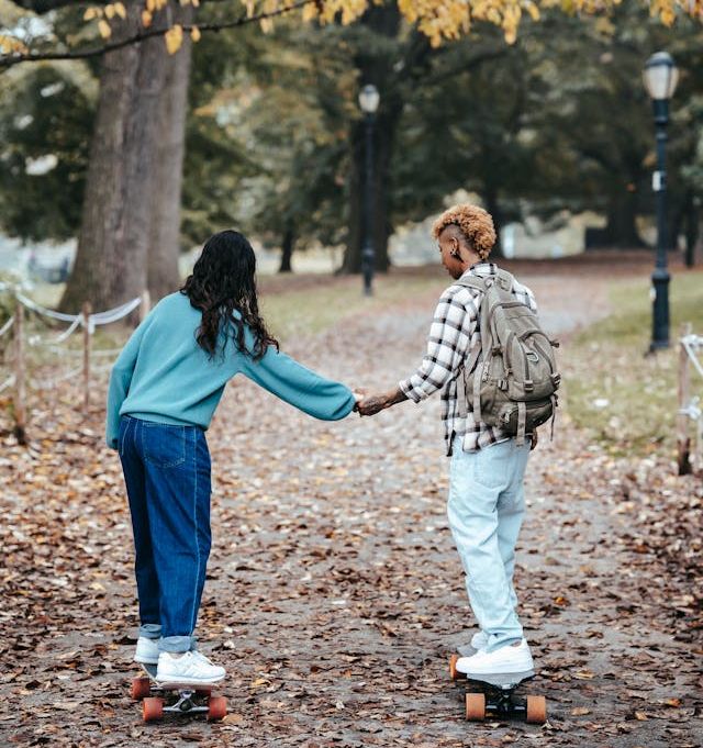 doua femei se dau pe skateboard intr-un parc toamna doua femei se dau pe skateboard intr-un parc toamna