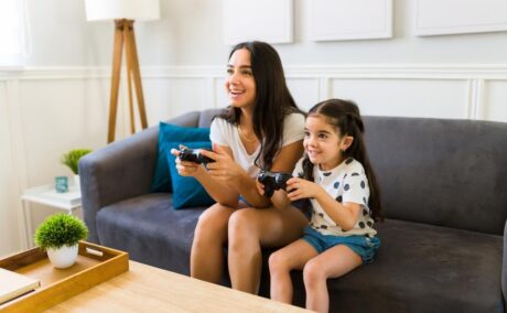 mama si fiica stand pe o canapea si jucandu-se un joc video