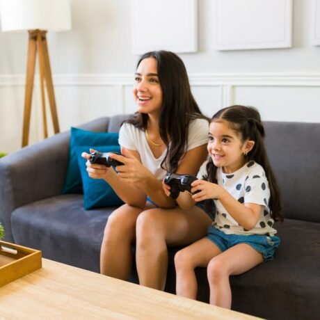 mama si fiica stand pe o canapea si jucandu-se un joc video